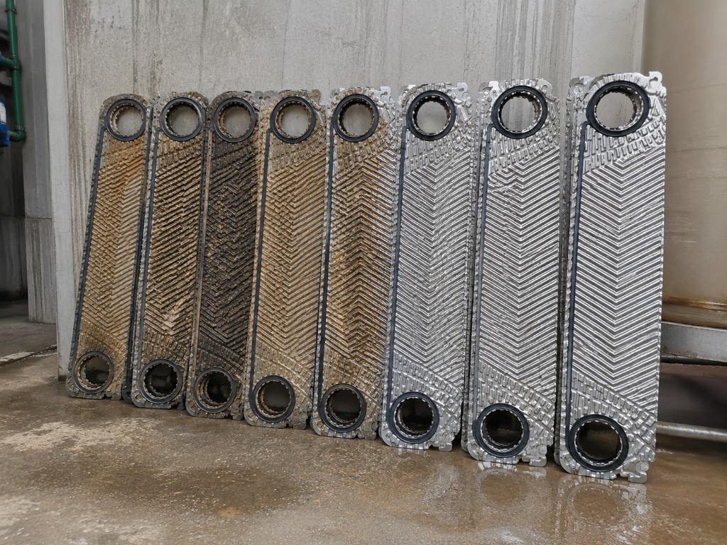 Row of heat exchanger plates showing the transition from heavily fouled to fully cleaned